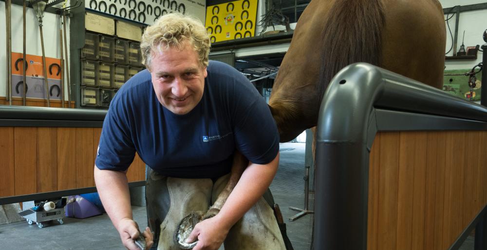 The German farrier Christoph Schweppe shoeing a horse