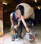 A farrier is shoeing a horse's back leg